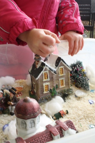 toddler scooping handful of rice in christmas sensory bin