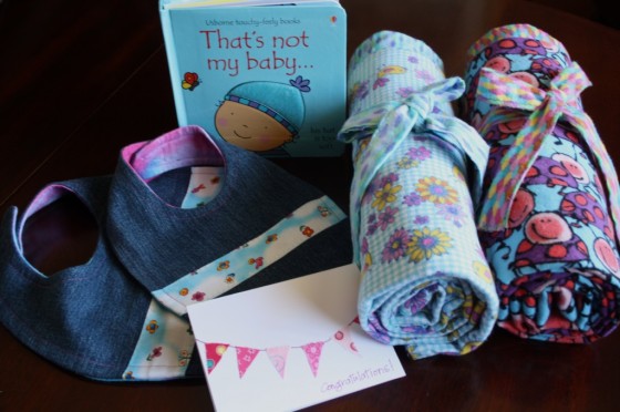 homemade baby blankets, bibs, card and a book