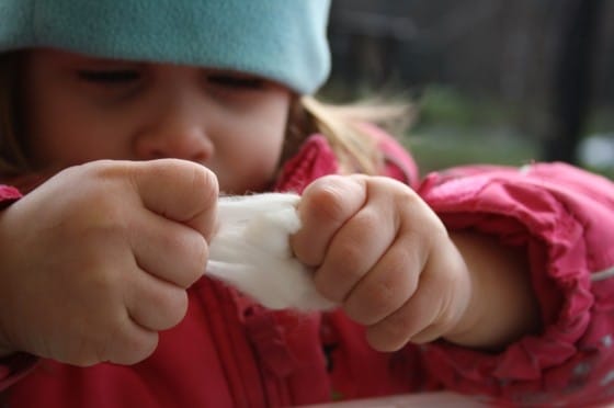 toddler pulling cotton ball apart