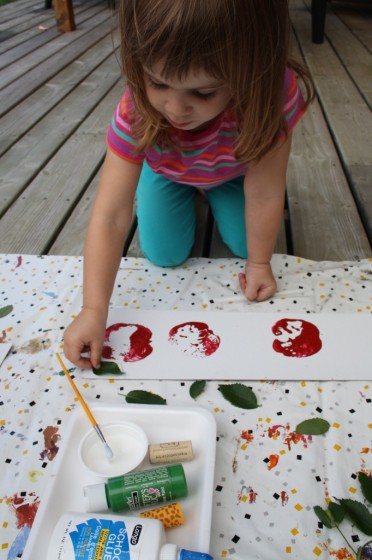 preschool girl gluing real leaf on apple stamping art