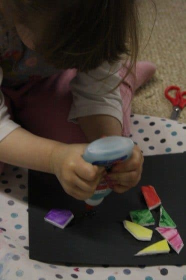 preschooler squeezing glue on black construction paper