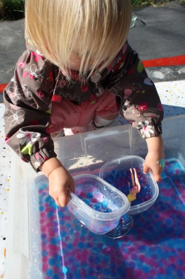 toddler playing with water beads sensory bin