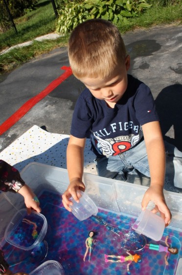 boy scooping water beads with containers