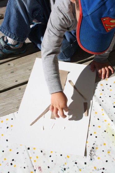 toddler using sandpaper to make an apple tree