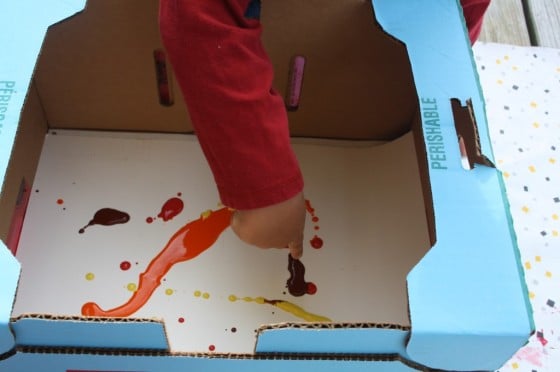 pouring paint on paper in a cardboard box