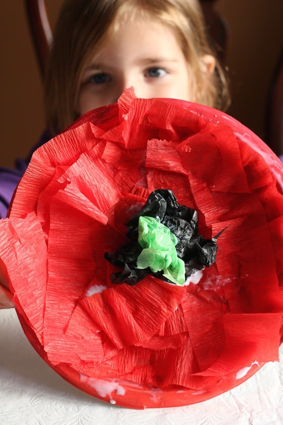 preschooler holding crepe paper poppy craft