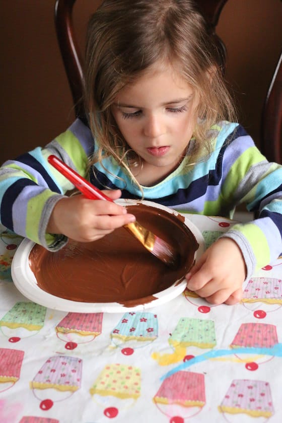 Child painting paper plate brown