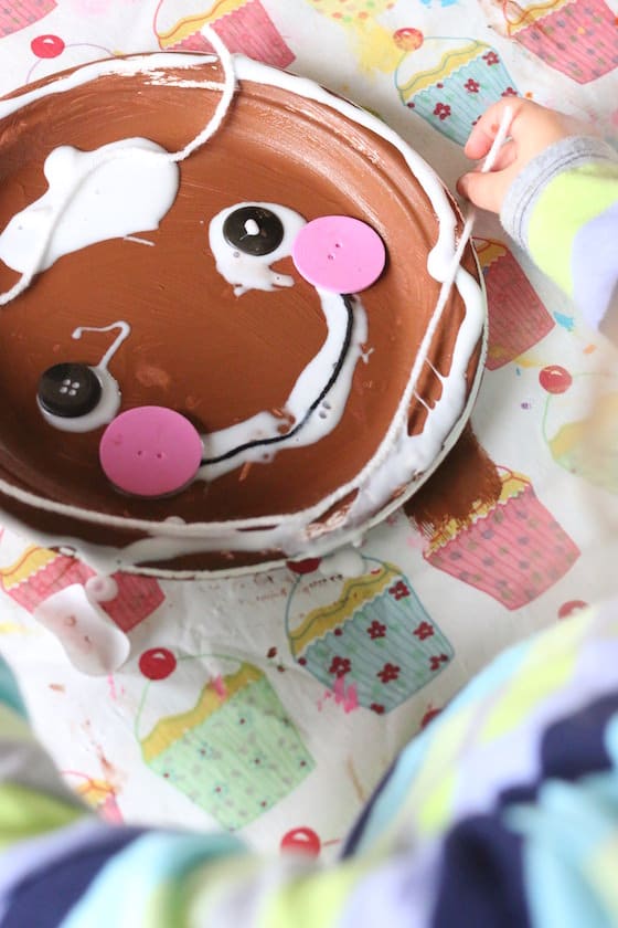 preschooler decorating a gingerbread man paper plate