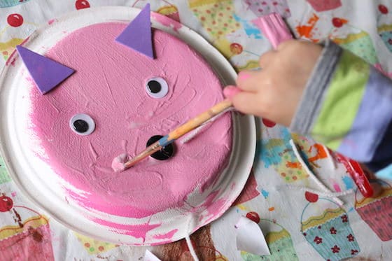 Child brushing glue onto paper plate