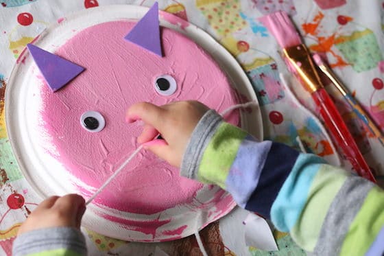 Child gluing whiskers on cat craft