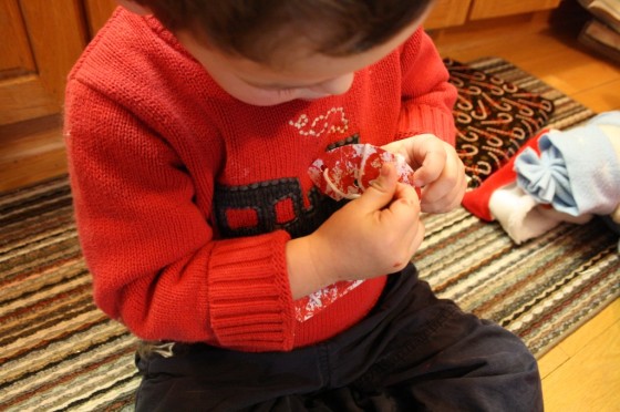 toddler lacing paper candy cane with white yarn