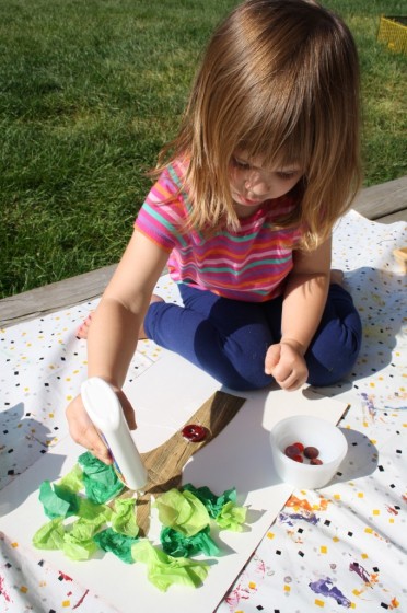 little girl squeezing glue onto apple tree craft