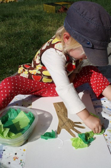 toddler gluing green tissue paper on apple tree craft