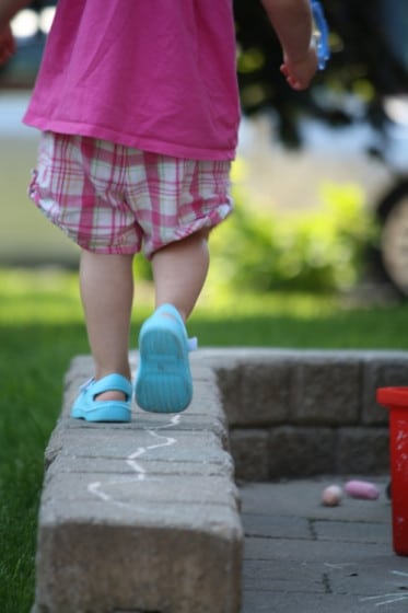 toddler balancing on low brick wall