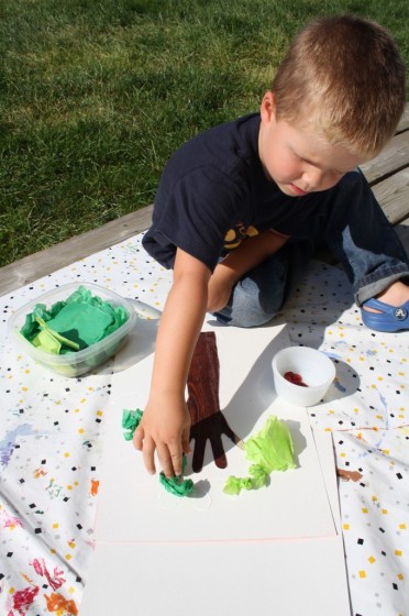 toddler gluing crumpled tissue paper on paper apple treet