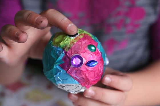 child gluing gems on tinfoil ornament