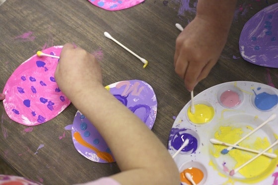 preschoolers painting with Q-tips on cardboard Easter Eggs