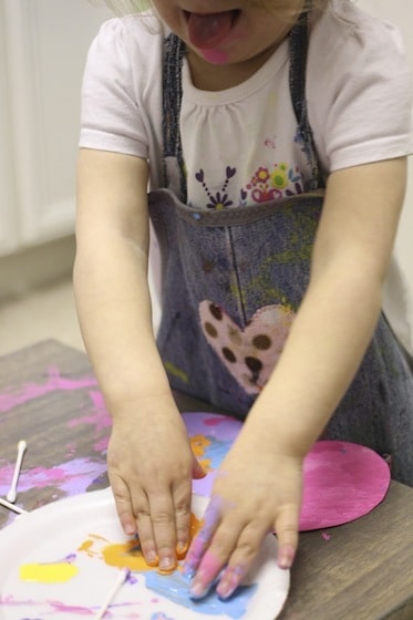 Toddler decorating easter eggs with her fingertips