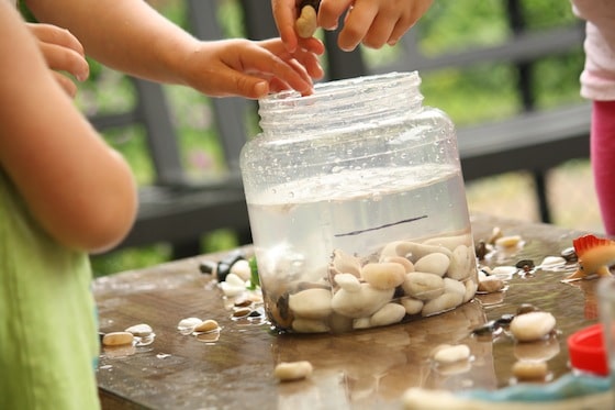 kids dropping stones into the container to raise the water level