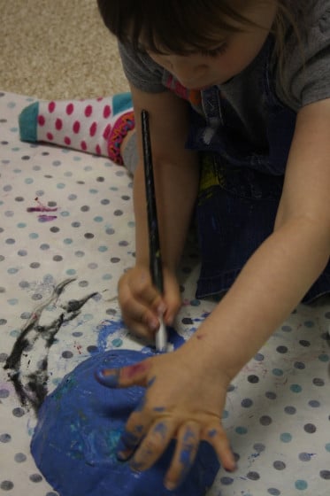 preschooler painting paper mache bowl blue