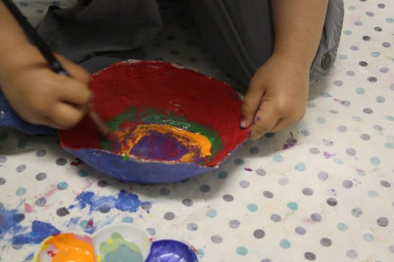 Toddler painting paper mache bowl