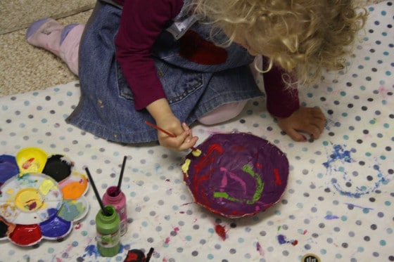 child painting paper mache bowl with acrylic craft paint