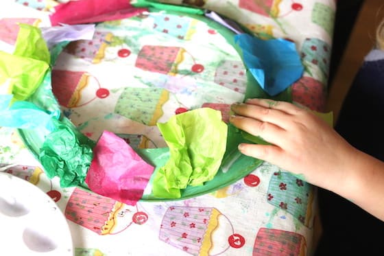 preschooler gluing tissue paper to paper plate