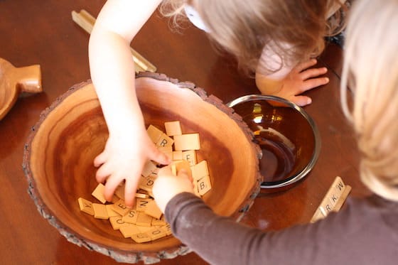 kids digging into bowl filled with scrabble tiles