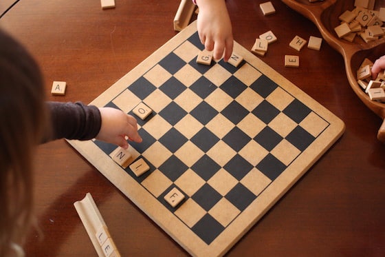 children placing scrabble letters on a checkerboard