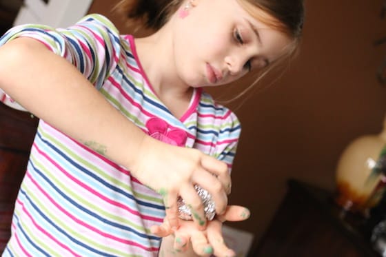 child covering styrofoam ball with tin foil