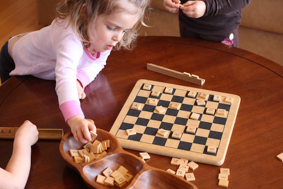 child holding handful of scrabble tiles