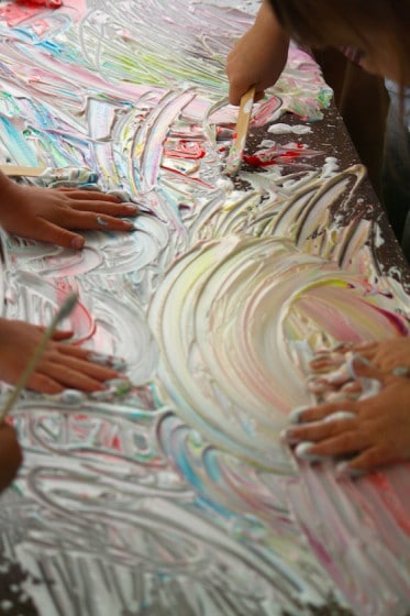 kids making art in coloured shaving cream with hands 