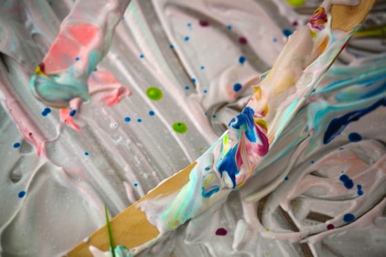 close up popsicle stick covered with shaving cream and food colouring