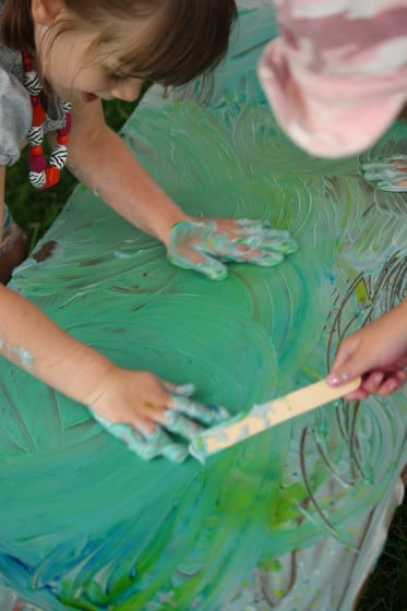 preschooler with both hands in green shaving cream