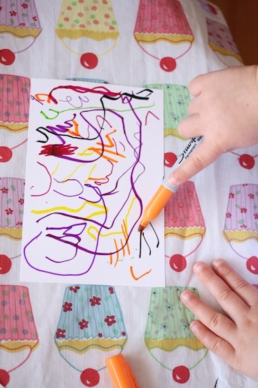 toddler making art on photo paper with a sharpies