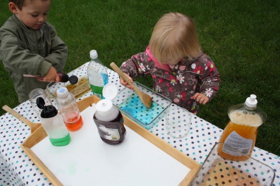 kids mixing coloured water in clear glass pans