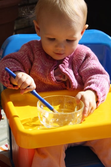 baby with paint brush and water