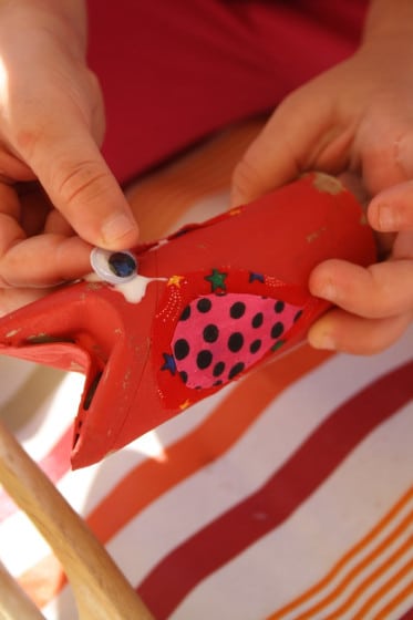 gluing googly eyes to toilet roll tube