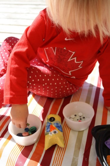 toddler making yellow owl with cardboard roll, fabric and buttons