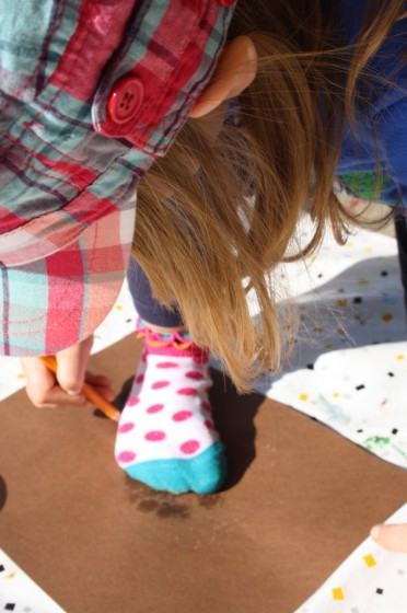 child tracing foot on construction paper for turkey body