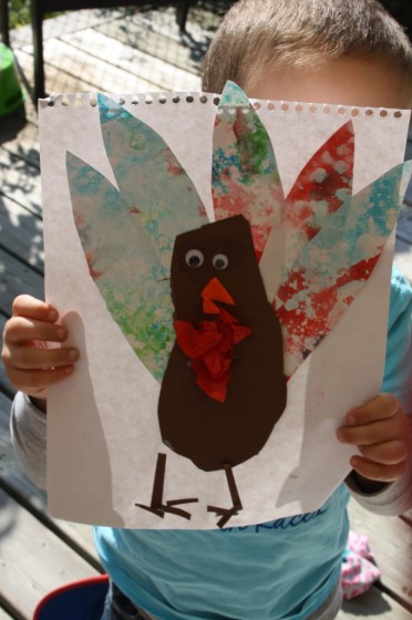 preschooler holding up finished bubble painting footprint turkey craft