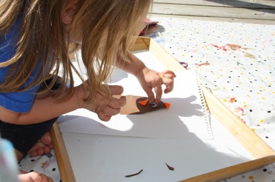 toddler gluing eyes on a footprint turkey craft