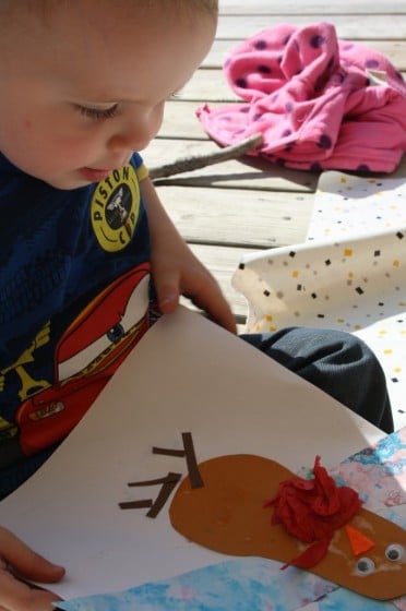 toddler boy admiring the turkey craft he made