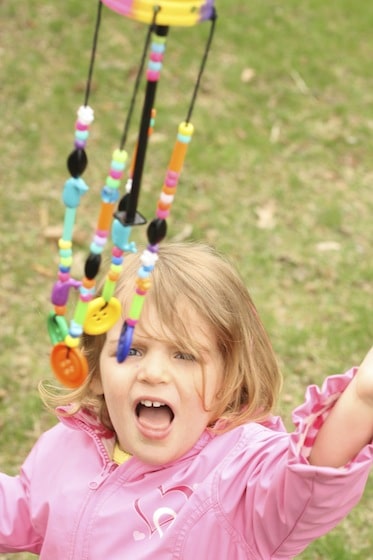 child batting at DIY wind chimes