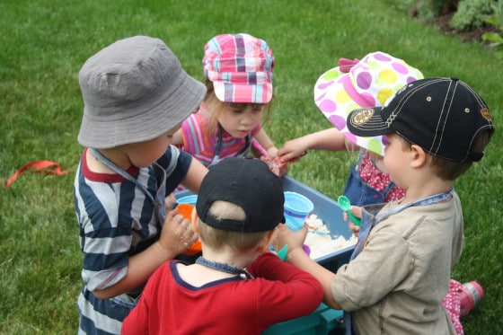 kids gathered round a bin of cloud dough in the backyard