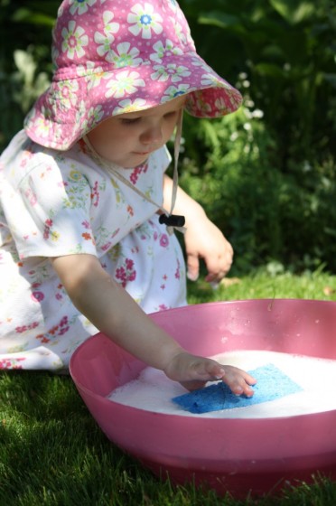 child playing with sponge in soapy water