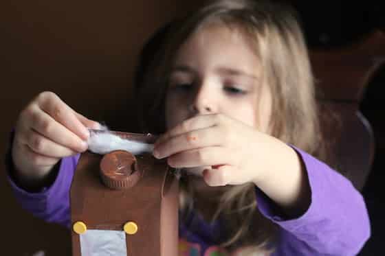 child gluing cotton balls on non-edible gingerbread house craft