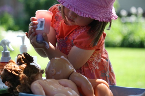 toddler squeezing shampoo on dolls hair