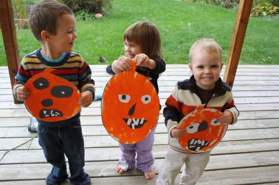 toddlers holding up painted jack o lantern craft