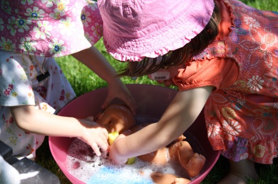 little girls washing dolls in soapy water